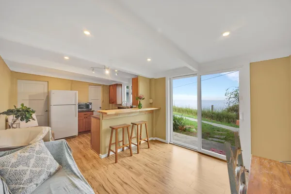 a kitchen with stainless steel appliances granite countertop a refrigerator a sink a stove and white cabinets with wooden floor