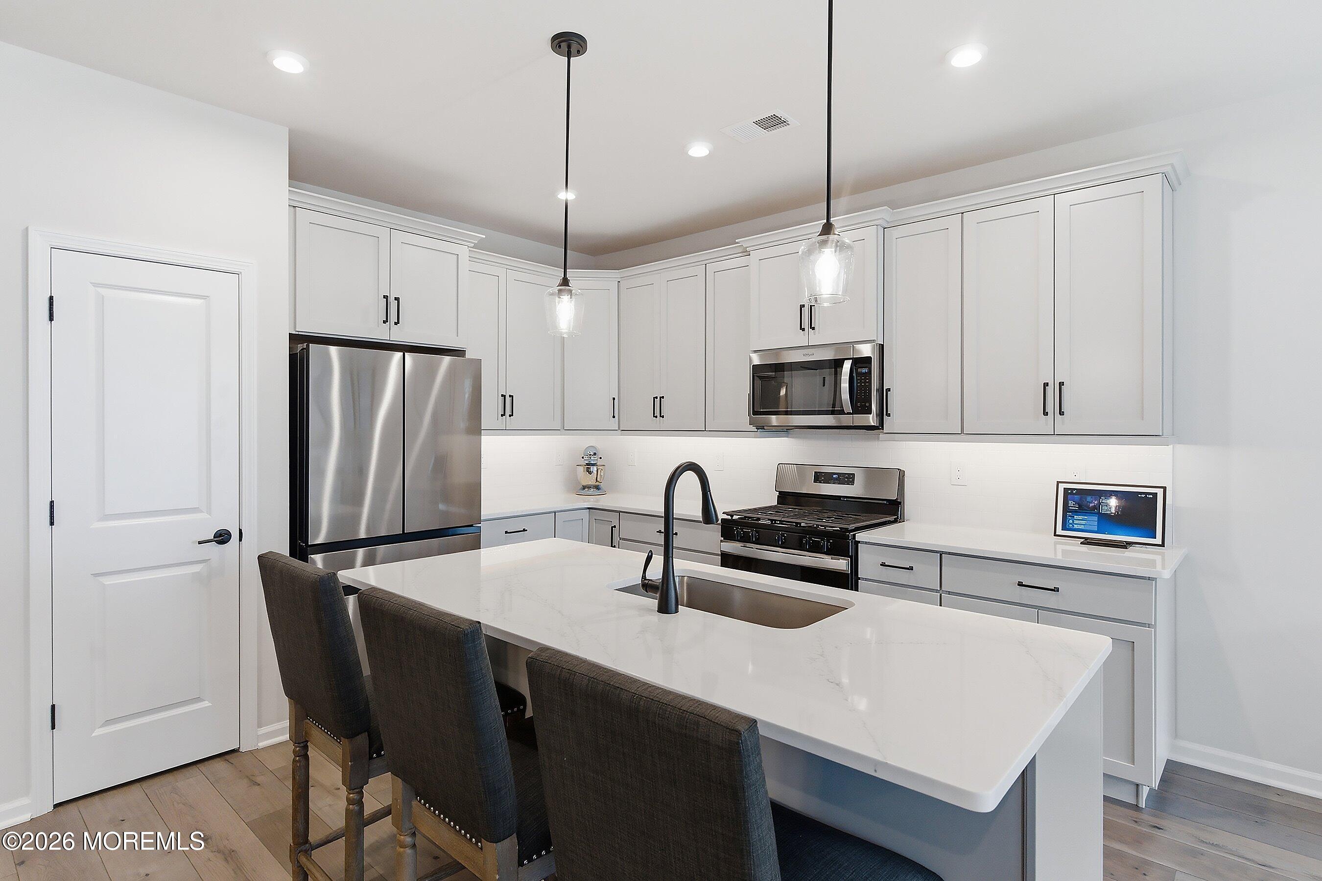5 Laird Way Neptune, NJ 07753 - Photo 7 of 35 a kitchen with stainless steel appliances a stove a sink island and a refrigerator with wooden floor