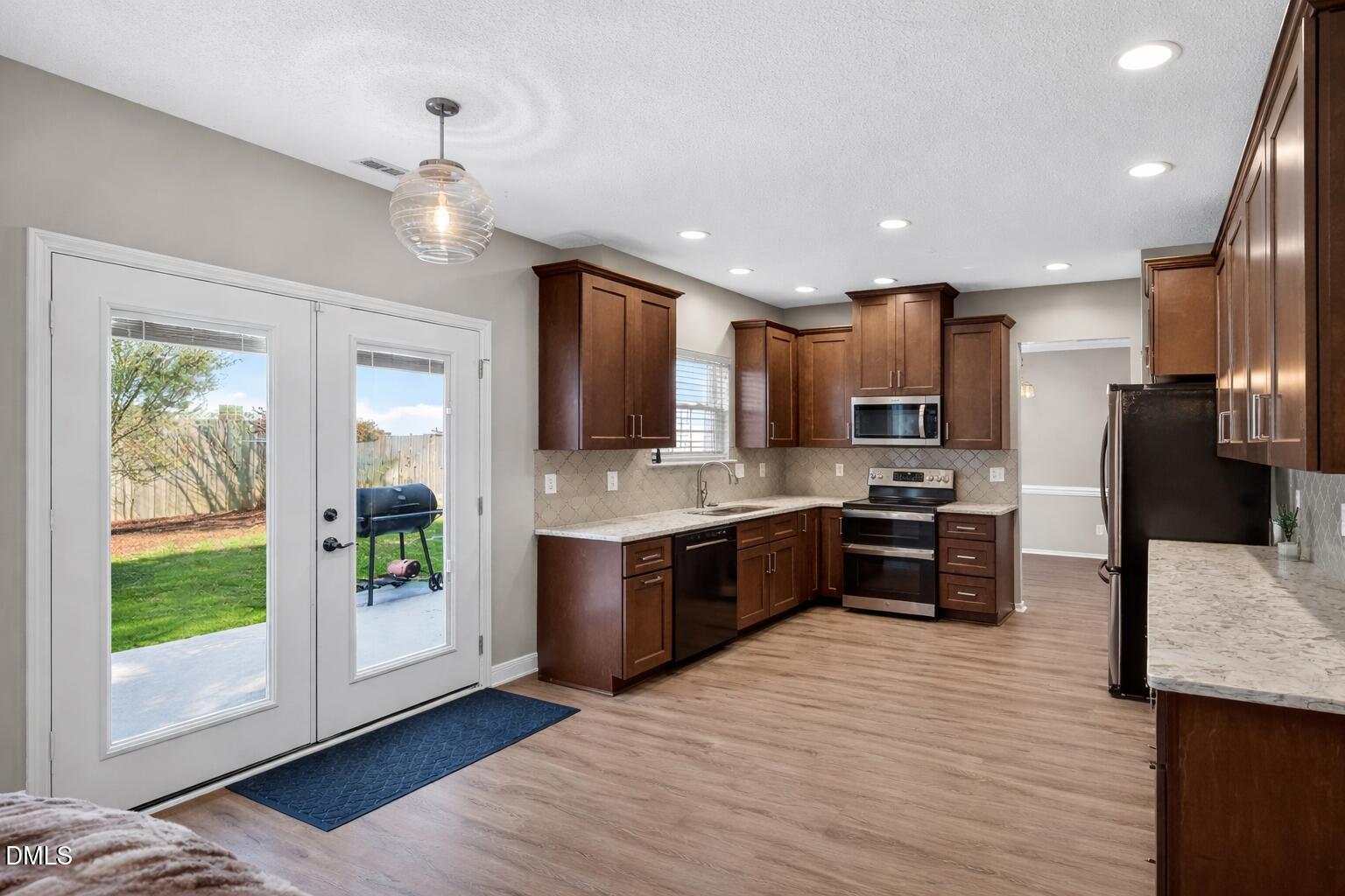5709 Apalachicula Drive Raleigh, NC 27616 - Photo 8 of 47 a kitchen with stainless steel appliances kitchen island granite countertop a refrigerator a sink dishwasher a stove and a dining table with wooden floor