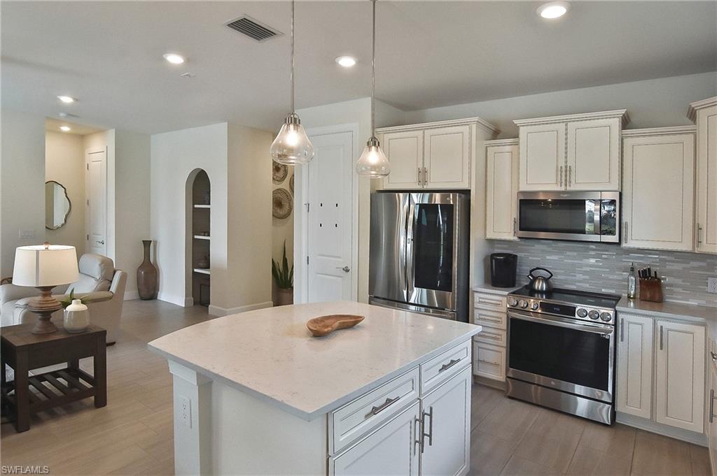 19375 Elston Way Estero, FL 33928 - Photo 30 of 50 a kitchen with stainless steel appliances granite countertop a sink a stove a refrigerator and island with wooden floor