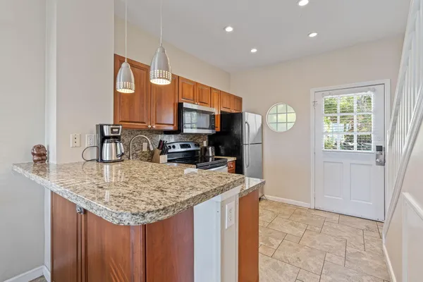 a kitchen with kitchen island granite countertop a sink stove and refrigerator