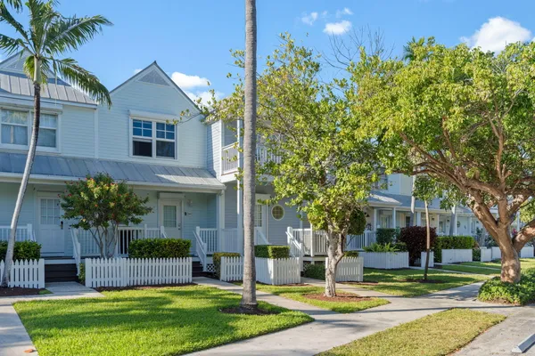 a view of a house with a yard and palm trees