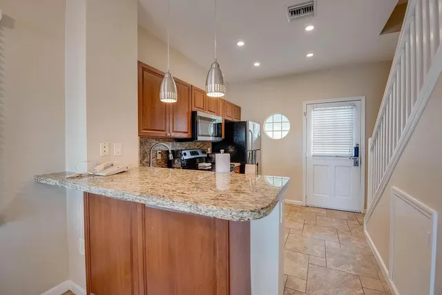 a kitchen with stainless steel appliances granite countertop a sink and a refrigerator