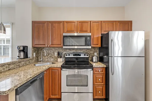 a kitchen with granite countertop a refrigerator stove and microwave