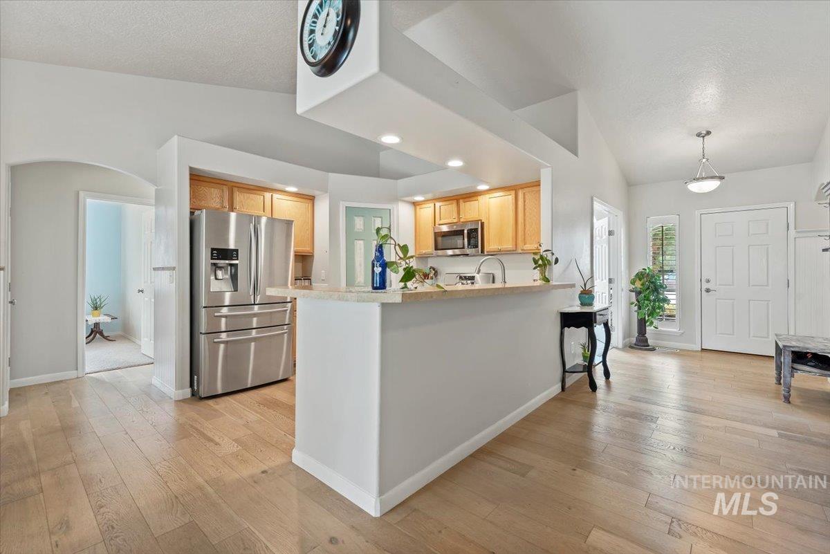 16608 Old Friendship Way Caldwell, ID 83607 - Photo 11 of 32 Kitchen with appliances with stainless steel finishes, light countertops, arched walkways, light wood-style floors, and a textured ceiling
