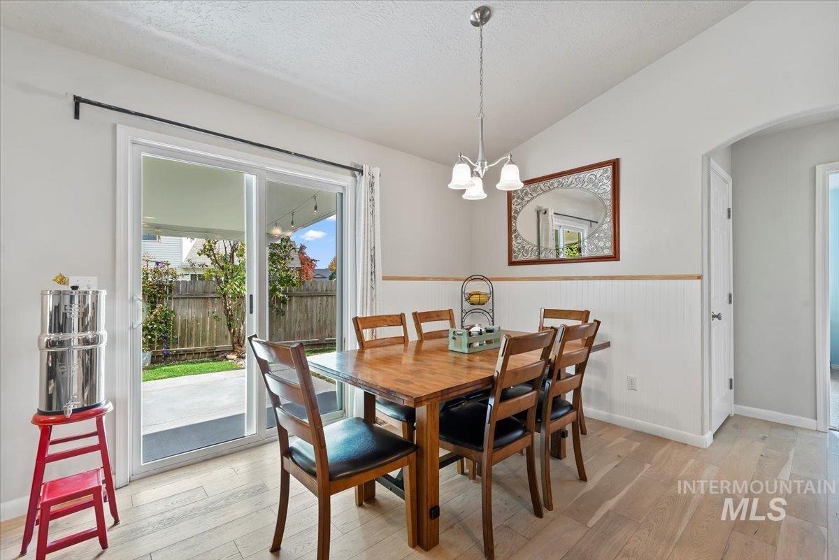 16608 Old Friendship Way Caldwell, ID 83607 - Photo 12 of 32 Dining room with vaulted ceiling, light wood-type flooring, a wainscoted wall, arched walkways, and a chandelier