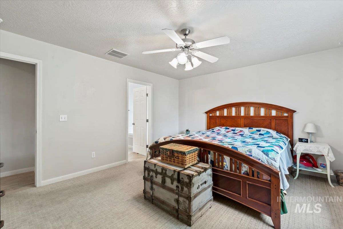 16608 Old Friendship Way Caldwell, ID 83607 - Photo 15 of 32 Bedroom featuring ceiling fan, light carpet, a textured ceiling, and connected bathroom