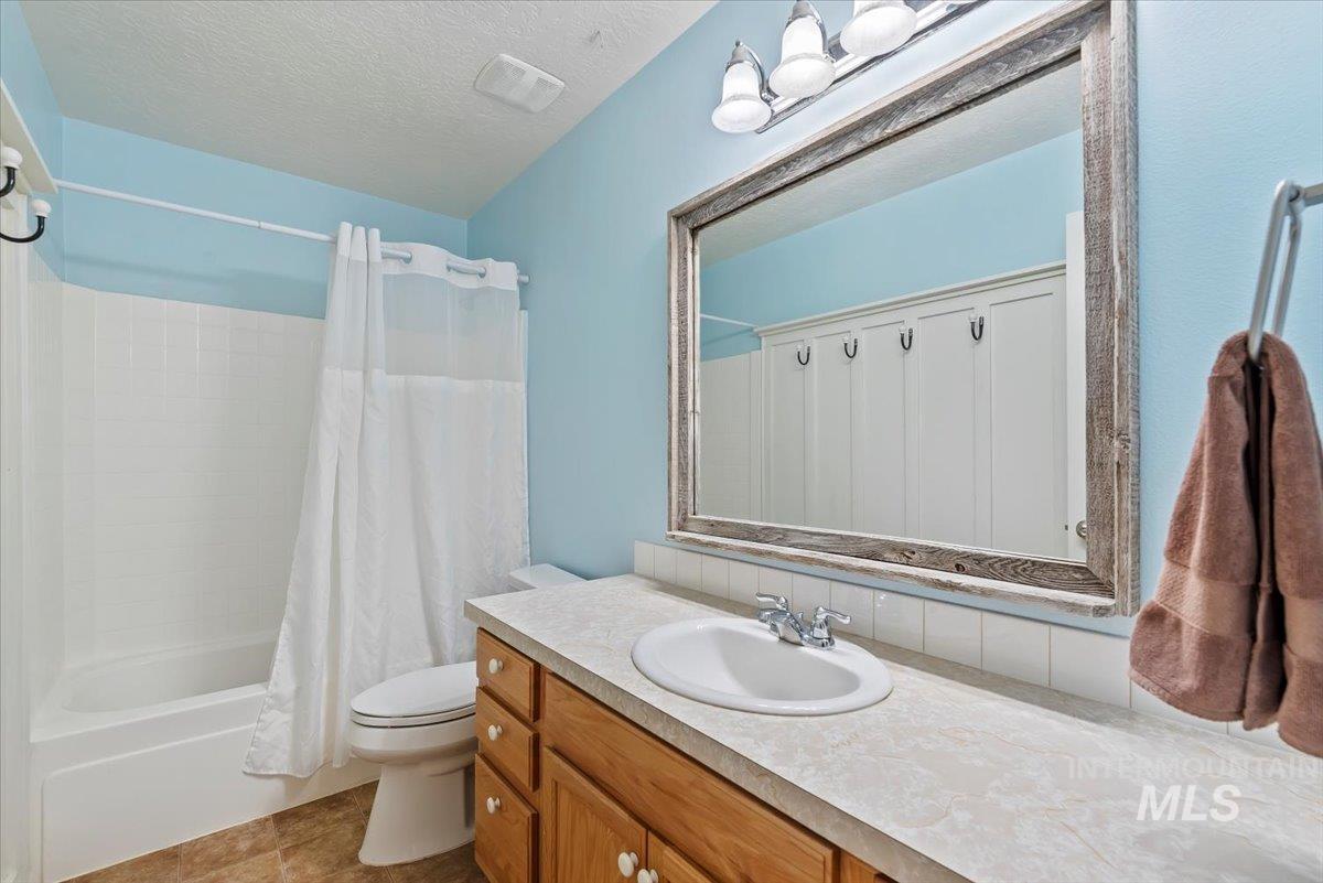16608 Old Friendship Way Caldwell, ID 83607 - Photo 20 of 32 Full bath with vanity, shower / bathtub combination with curtain, a textured ceiling, and light tile patterned floors