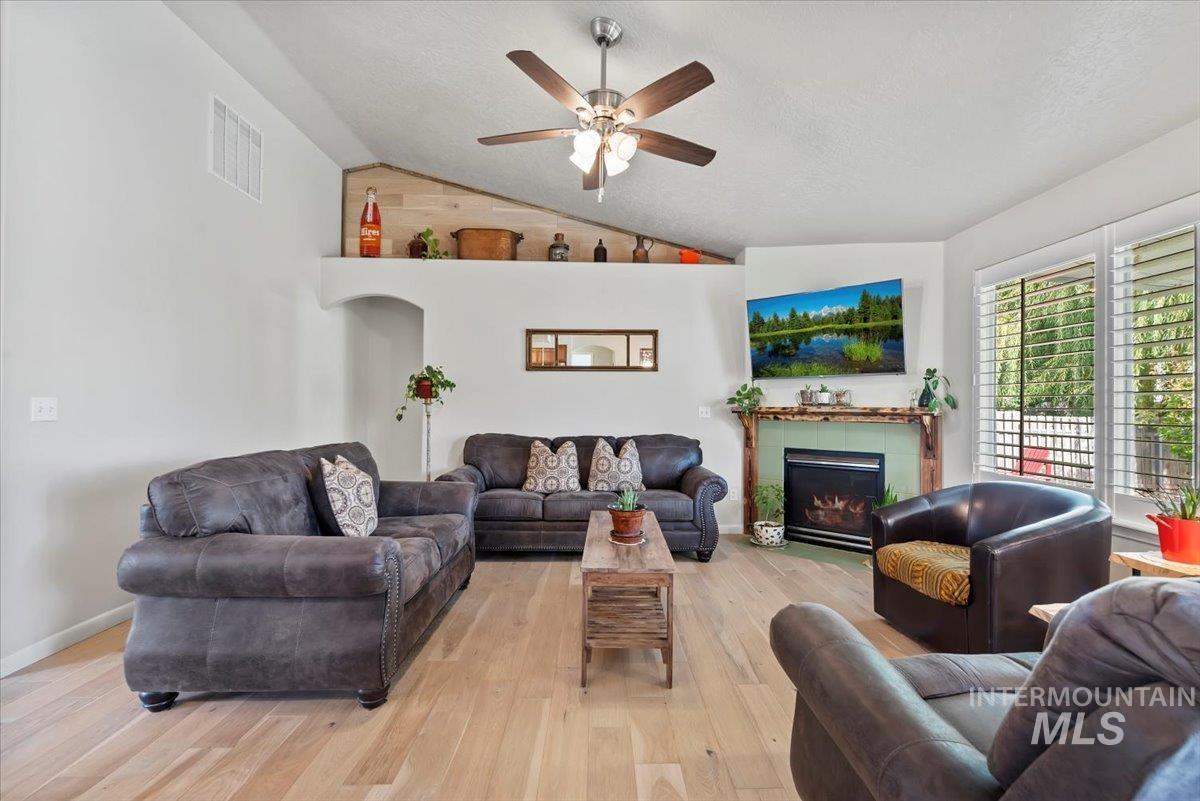 16608 Old Friendship Way Caldwell, ID 83607 - Photo 7 of 32 Living area featuring wood finished floors, lofted ceiling, a fireplace, ceiling fan, and a textured ceiling
