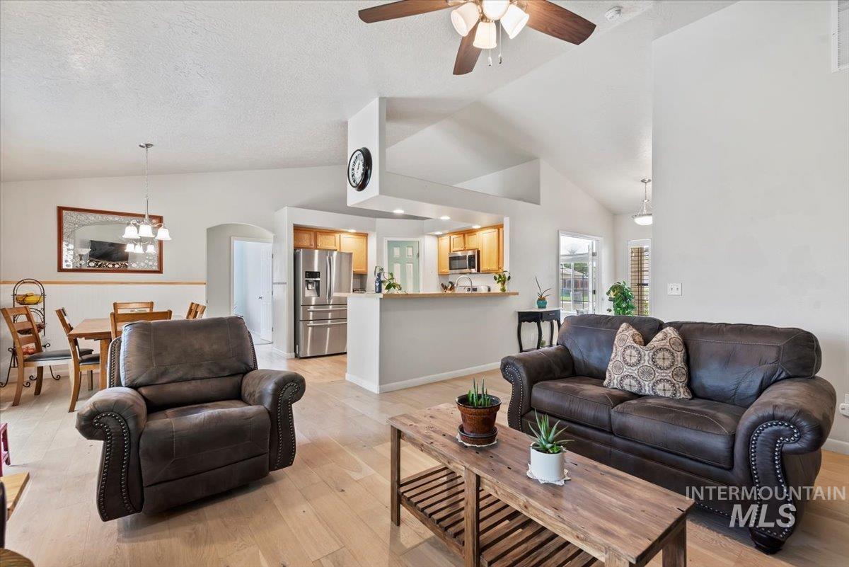 16608 Old Friendship Way Caldwell, ID 83607 - Photo 8 of 32 Living room with vaulted ceiling, light wood finished floors, arched walkways, ceiling fan, and a textured ceiling
