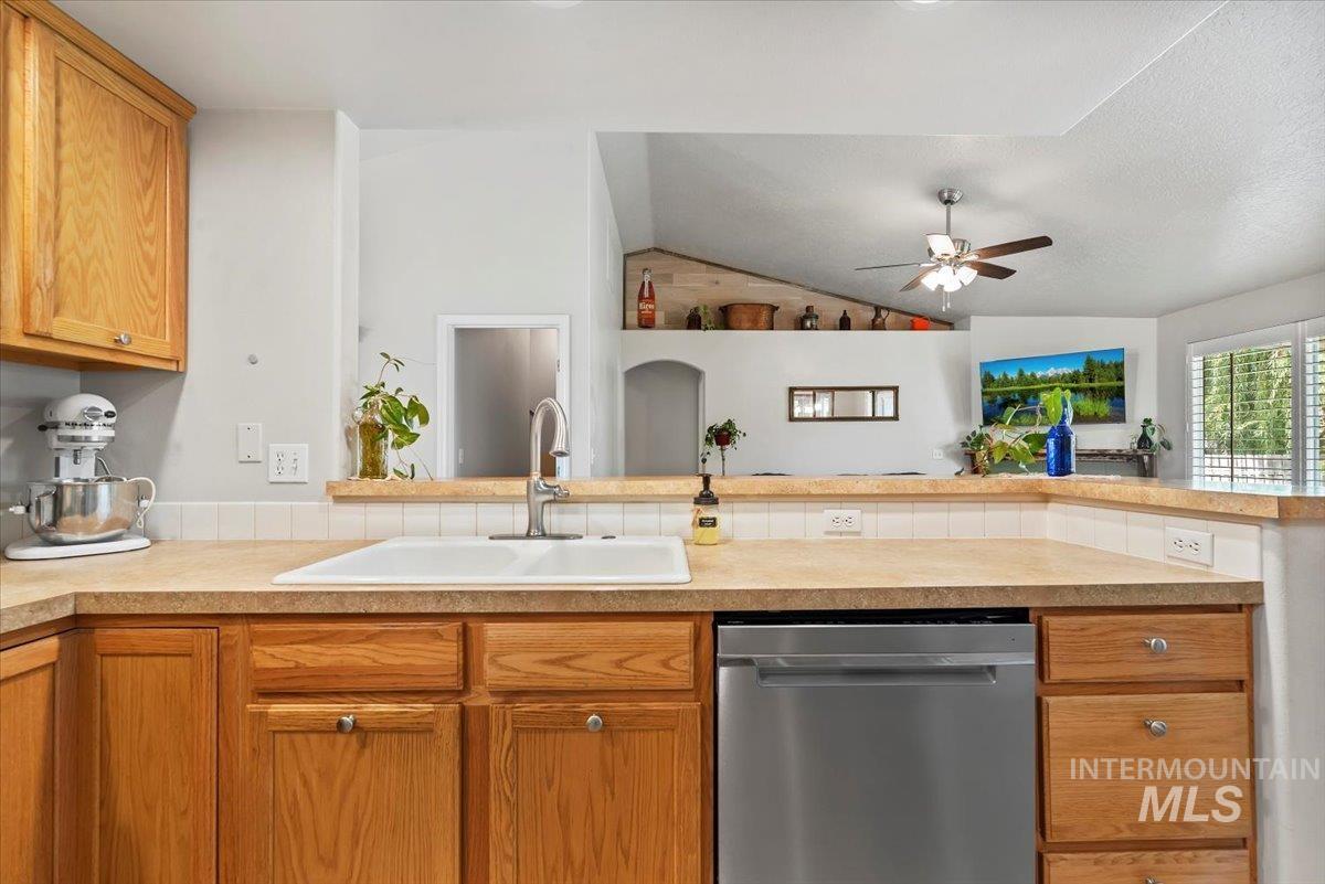 16608 Old Friendship Way Caldwell, ID 83607 - Photo 10 of 32 Kitchen with dishwasher, light countertops, vaulted ceiling, brown cabinets, and a ceiling fan