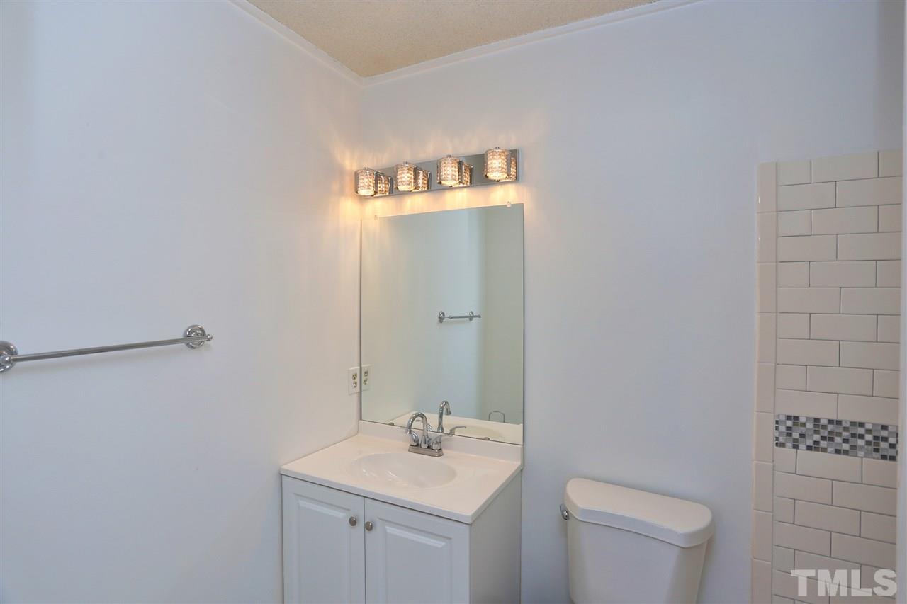 4465 Roller Court Raleigh, NC 27604 - Photo 12 of 23 a bathroom with a toilet sink vanity and mirror
