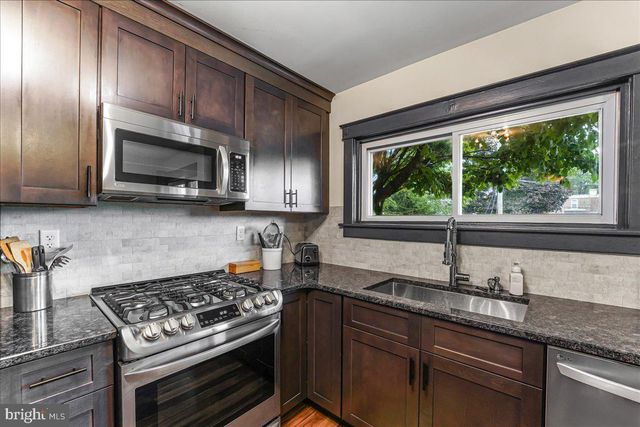 a kitchen with granite countertop wooden cabinets stove top oven and sink