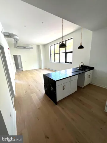 a spacious bathroom with a granite countertop sink a toilet a mirror and a shower