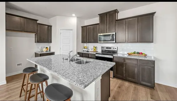 a kitchen with granite countertop kitchen island stainless steel appliances a sink stove and refrigerator