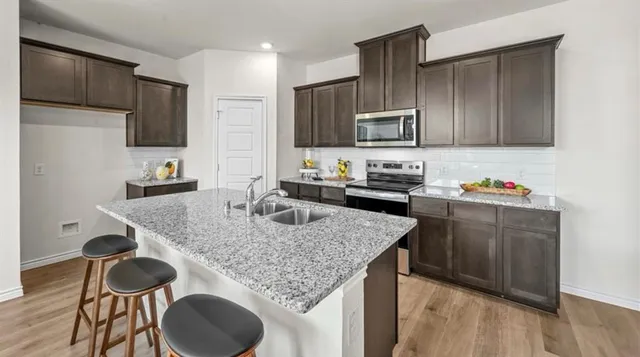 a kitchen with granite countertop kitchen island stainless steel appliances a sink stove and refrigerator