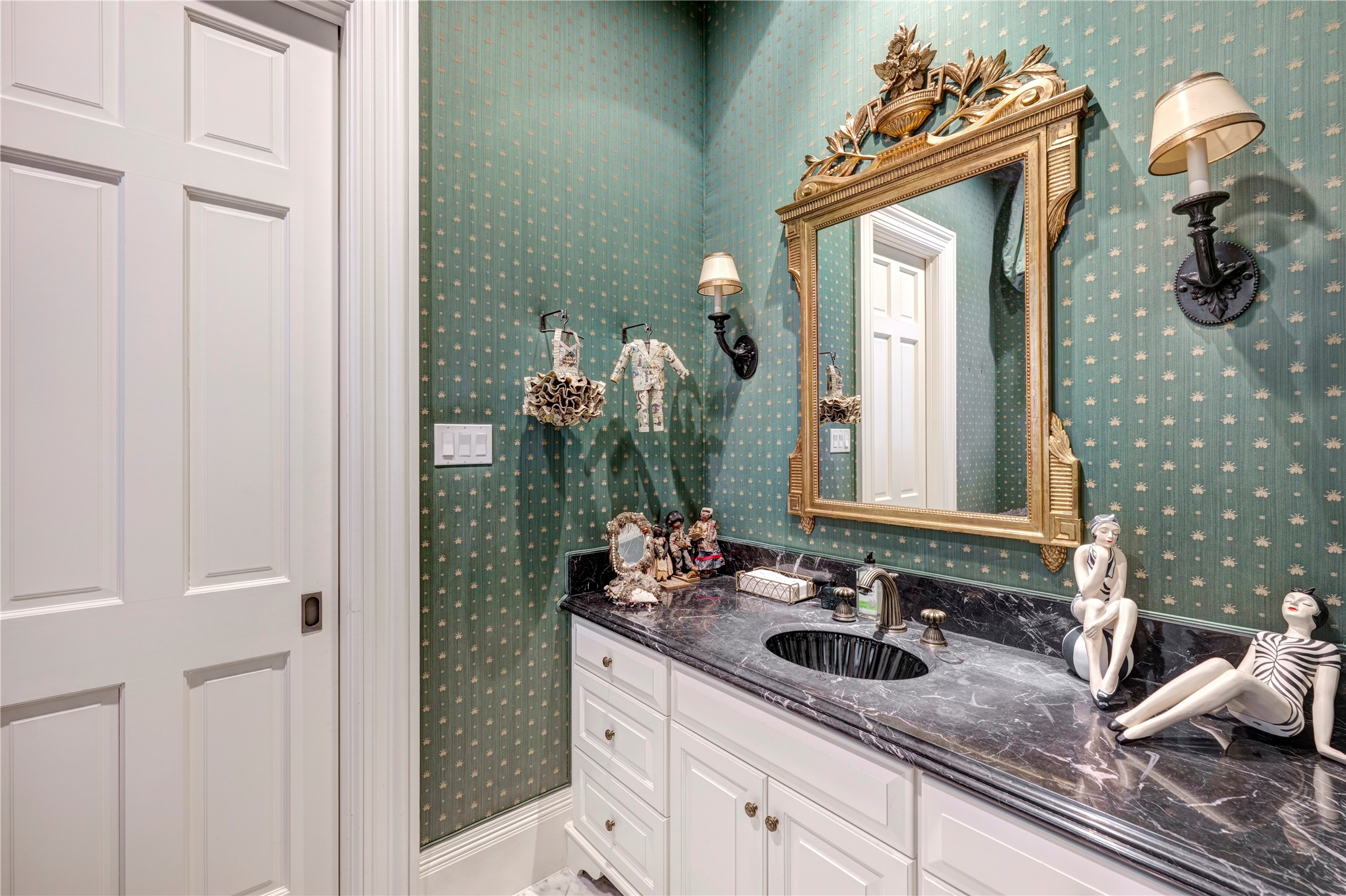 3653 Inverness Drive Houston, TX 77019 - Photo 18 of 39 The first-floor powder room is furnished with an elegant mirror, marble countertops, marble flooring, and sconces, enhancing the aesthetic and functional qualities of the space..