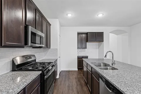 a kitchen with granite countertop stainless steel appliances a sink stove top oven and cabinets