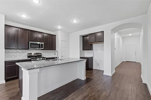 a kitchen with stainless steel appliances granite countertop a stove top oven a sink and dishwasher a refrigerator with wooden floor