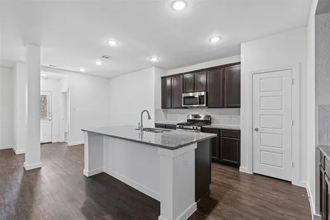 a kitchen with stainless steel appliances granite countertop a stove top oven a sink and a refrigerator