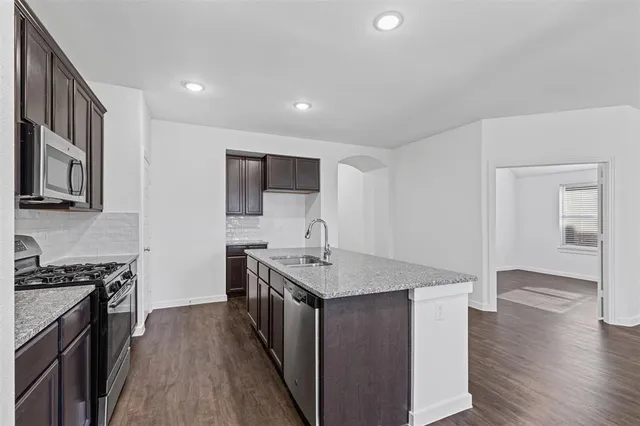 a kitchen with stainless steel appliances granite countertop a stove a sink and a refrigerator