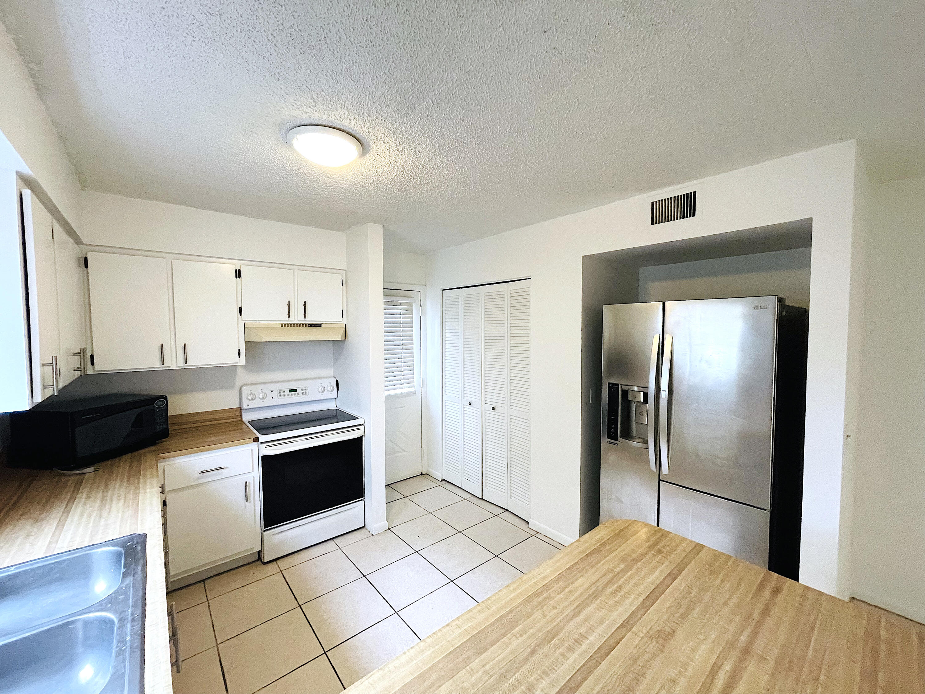308 Hernando Street, Unit A Fort Pierce, FL 34949 - Photo 4 of 9 a kitchen with stainless steel appliances kitchen island granite countertop a refrigerator and a stove top oven
