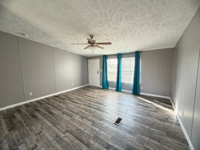 a view of an empty room with window and wooden floor