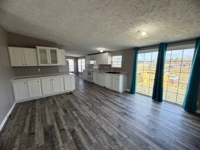 a living room with stainless steel appliances wooden floors and view kitchen