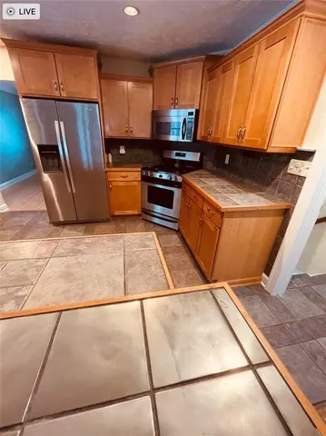 a kitchen with stainless steel appliances a refrigerator a stove a sink a counter top space and cabinets