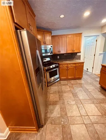 a kitchen with stainless steel appliances granite countertop a refrigerator and a stove