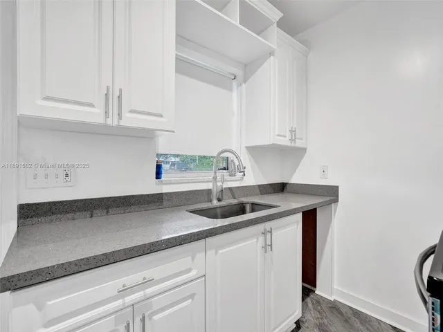 a kitchen with granite countertop white cabinets and a sink