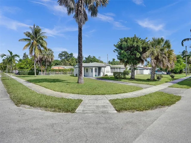 a view of a house with a yard and palm trees