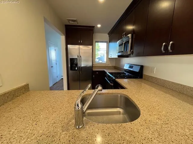 a kitchen with stainless steel appliances kitchen island sink refrigerator and stove