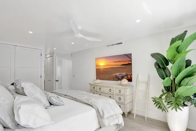 a bedroom with a large bed and a flat tv screen on dresser