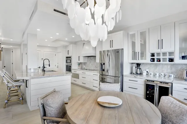 a kitchen with stainless steel appliances granite countertop a sink a stove a refrigerator cabinets and chairs