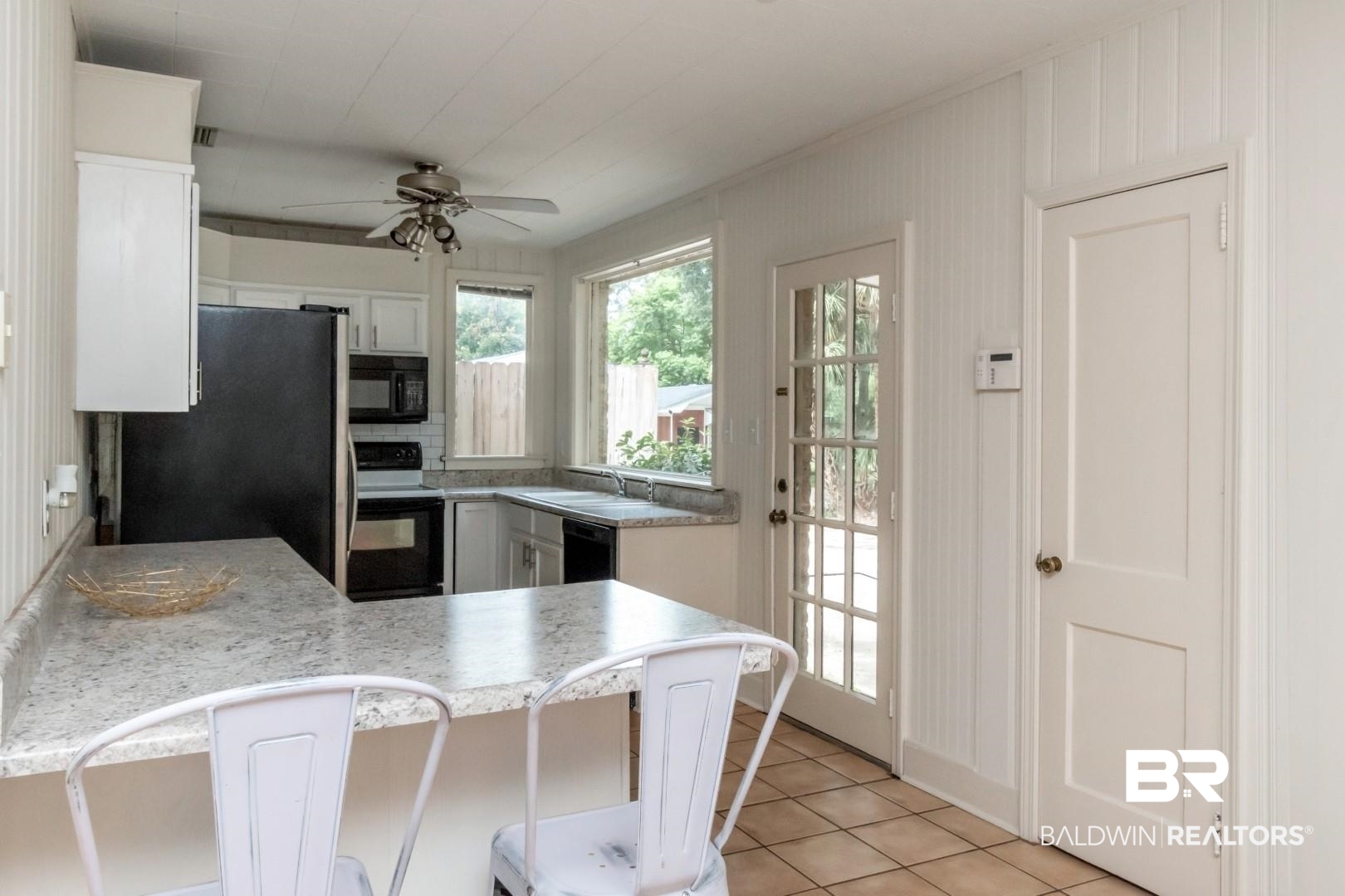 1906 Old Shell Road Mobile, AL 36607 - Photo 11 of 26 Kitchen with light tile patterned flooring, black appliances, white cabinetry, ceiling fan, and kitchen peninsula