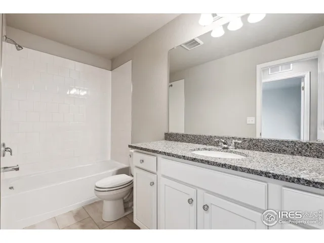 a bathroom with a granite countertop sink a toilet a mirror and bathtub