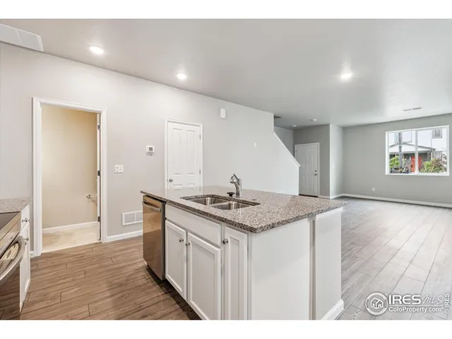 a kitchen with stainless steel appliances granite countertop a sink and wooden floor