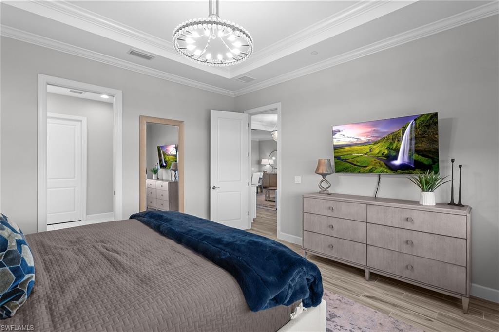 9673 Montelanico Loop, Unit 202 Naples, FL 34119 - Photo 13 of 46 a bedroom with a chandelier and a dresser