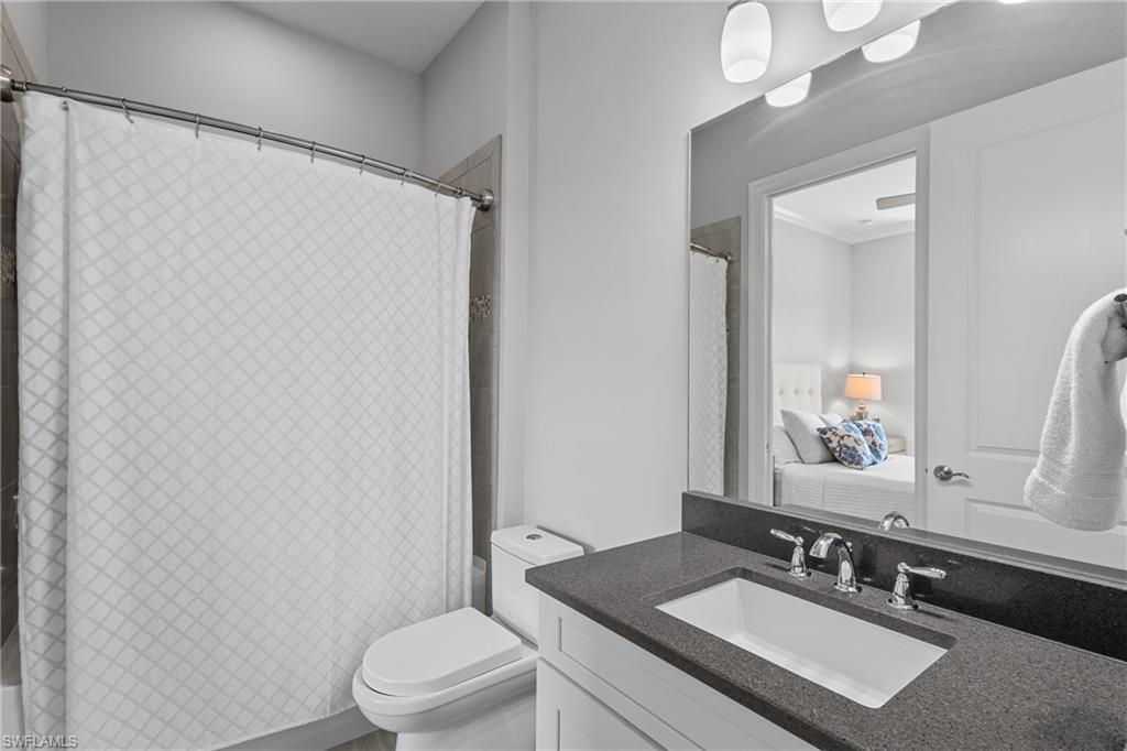 9673 Montelanico Loop, Unit 202 Naples, FL 34119 - Photo 19 of 46 a bathroom with a sink vanity mirror and toilet