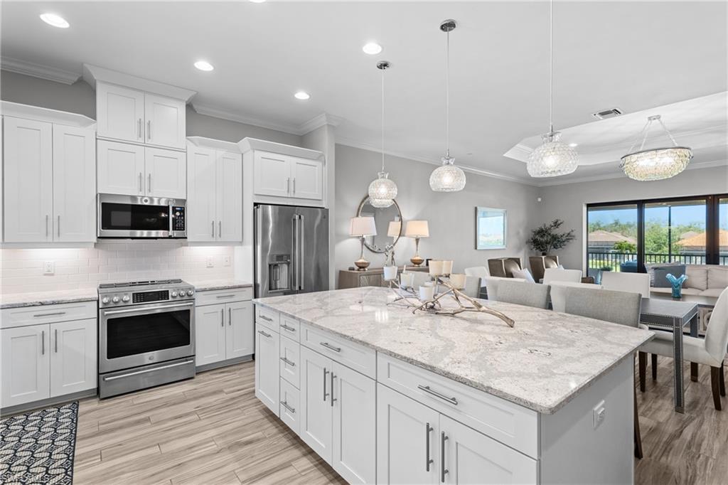 9673 Montelanico Loop, Unit 202 Naples, FL 34119 - Photo 2 of 46 a kitchen with stainless steel appliances granite countertop a stove top oven a sink dishwasher and a refrigerator with the cabinets