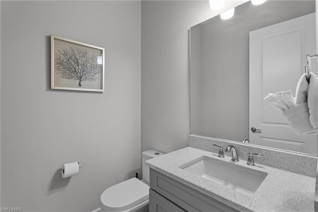 9673 Montelanico Loop, Unit 202 Naples, FL 34119 - Photo 23 of 46 a bathroom with a granite countertop toilet sink and mirror