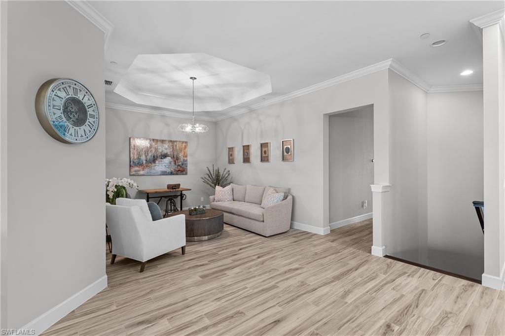 9673 Montelanico Loop, Unit 202 Naples, FL 34119 - Photo 10 of 46 a living room with furniture a clock and wooden floor