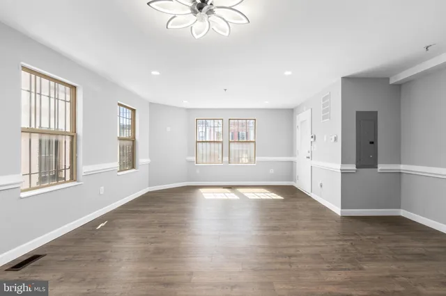 a view of an empty room with a window and wooden floor