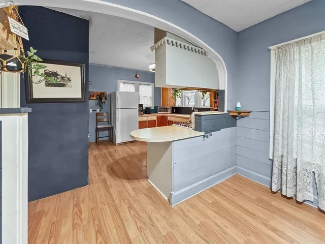 a living room with stainless steel appliances furniture a rug and a kitchen view