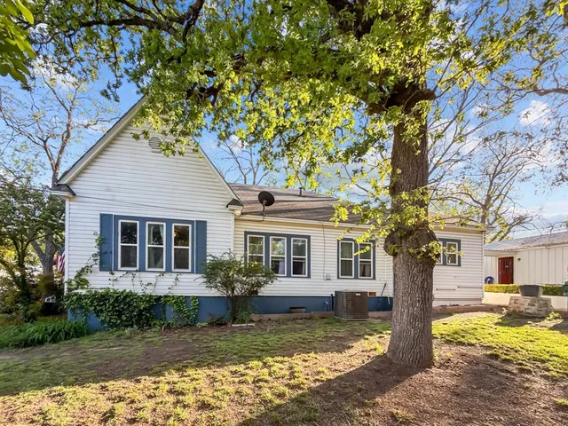 a view of a yard in front of a house with large tree