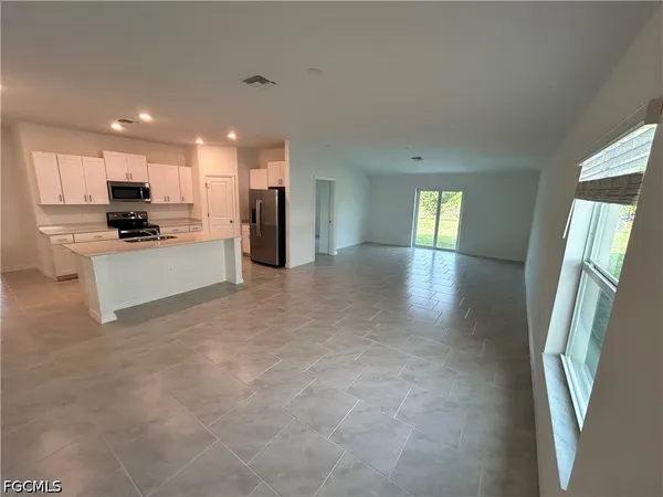 a view of a electric appliances in kitchen and an empty room