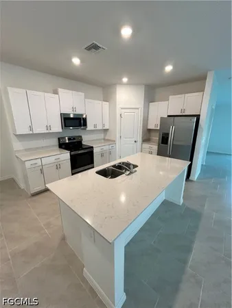 a kitchen with kitchen island a sink a stove a refrigerator and cabinets