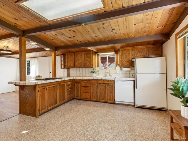 a kitchen with sink a refrigerator and wooden cabinets