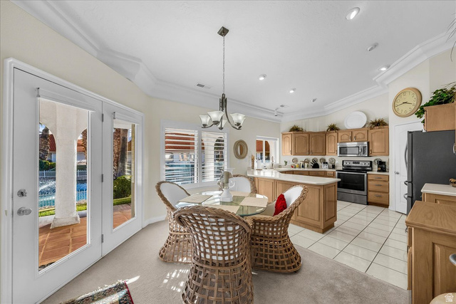 150 South Crystal Street, Unit 31 St. George, UT 84770 - Photo 11 of 20 Dining area with lofted ceiling, hanging lights, ornamental molding, light colored carpet, and light tile patterned floors